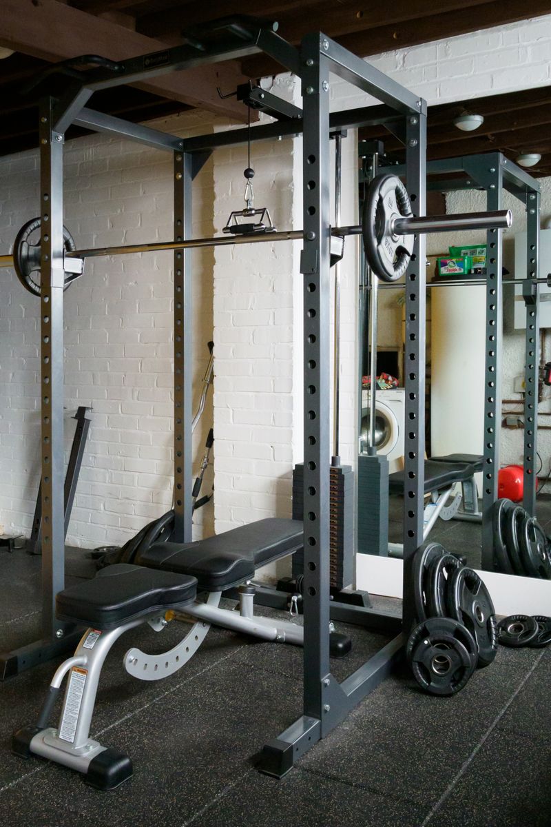 A well-equipped gym featuring a barbell setup with weights and a mirror.